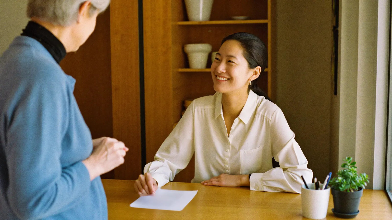 Front-desk coordinator sharing the quoted price with a patient at a clinic checkout desk.