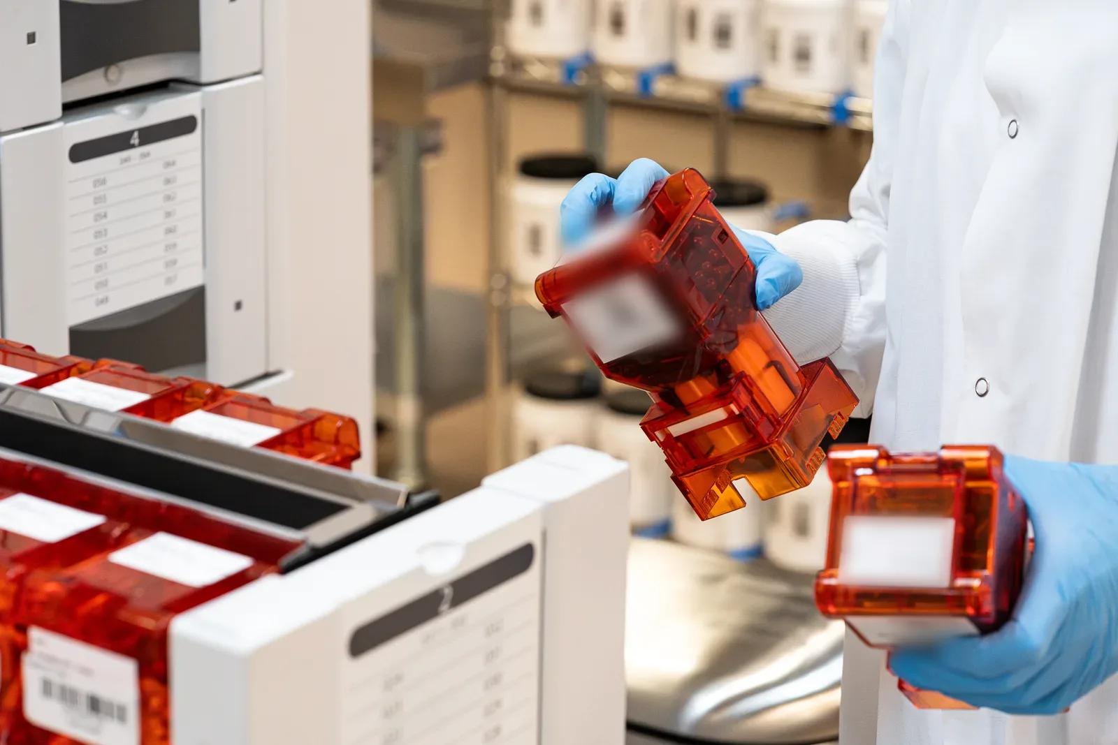 A gloved technician checking labelled ingredient cartridges on the production line.